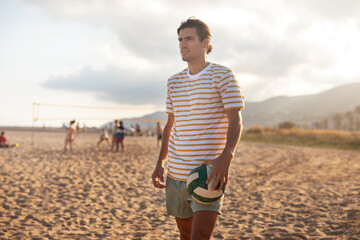 Young man with ball at the beach. Handsome man playing volleyball.