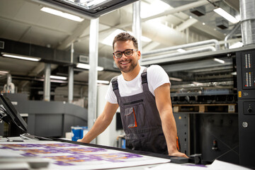 Portrait of worker at control room checking print quality at printing house.