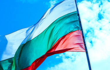 Tree-colored white, green and red Bulgarian flag waving on the blue sky background.