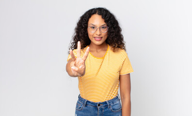 pretty hispanic woman smiling and looking friendly, showing number three or third with hand...