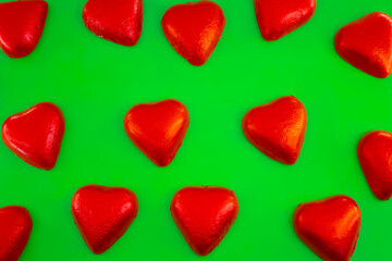 Chocolate candies shape of hearts on green background