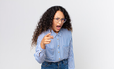 pretty hispanic woman pointing at camera with an angry aggressive expression looking like a...