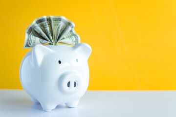 White piggy bank on the table and yellow background save money concept.