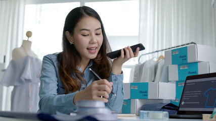 Young asia seller woman happy work on laptop busy cellphone call chat to customer at home office...