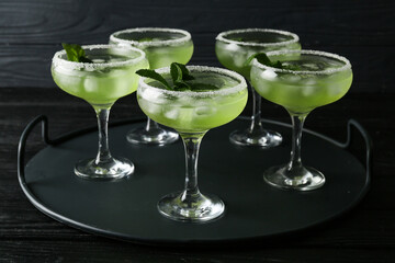 Tray with glasses of cold daiquiri cocktail on dark background