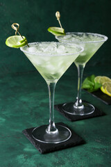 Glasses of cold daiquiri cocktail on color background