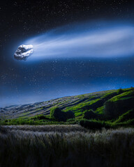 Large comet with a long tail at night against a starry sky over fields and green hills. A comet falls to Earth in a field.
