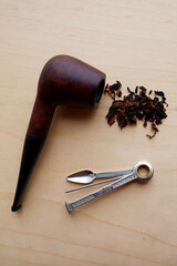 Fototapeta na wymiar Smoking pipe and tamper lie on a wooden table