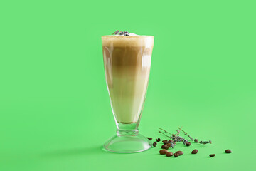 Glass of tasty lavender latte on color background