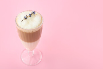 Glass of tasty lavender latte on color background