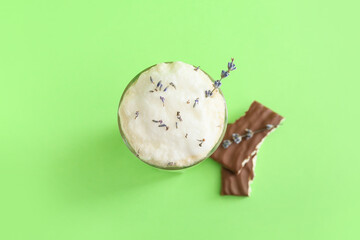 Glass of tasty lavender latte and chocolate on color background