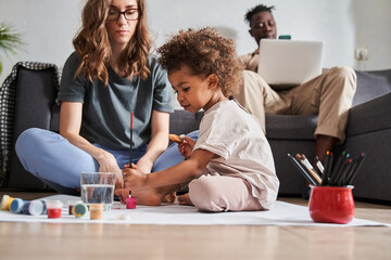 Girl sitting at floor and drawing her picture with calmness at floor at the living room