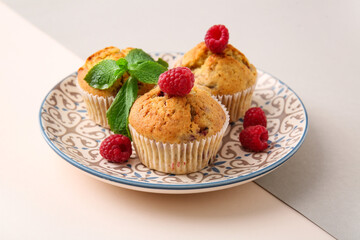 Plate with tasty raspberry muffins on color background, closeup