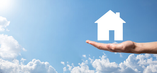 Naklejka premium Male hand holding house icon on blue background. Property insurance and security concept.Real estate concept.Banner with copy space.