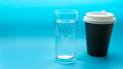Glass with water and a cup for coffee, isolated on a blue background. Copyspace.