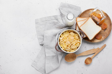 Composition with tasty cornflakes and milk on light background