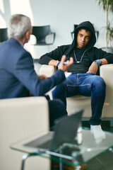 Black male adolescent talks to counsellor during session at psychotherapy center.