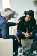 Mature psychotherapist encourages black male adolescent during therapy at counselling center.