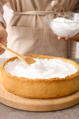 Woman cooking tasty pie at table in kitchen, closeup