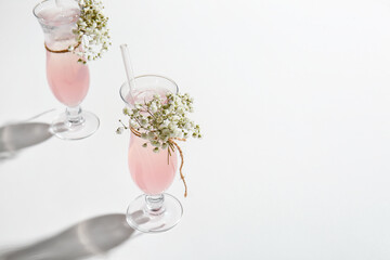 Glasses with tasty cocktail and beautiful gypsophila flowers on white background