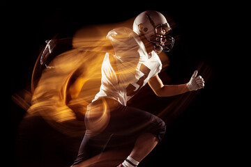 Fototapeta na wymiar Portrait of young man, American football player training isolated on dark studio background with mixed neon light. Concept of sport, competition and beauty