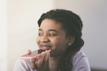 Portrait of a young afro woman talking on a smartphone who looks to the side and smiles