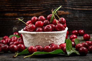 Cherry. Fresh sweet cherries bowl with leaves on wooden desktop table. water drops on Fresh sour cherry berries