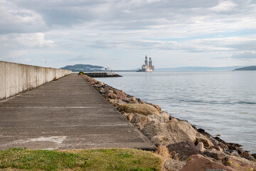 Obraz premium The marina wall in Largs with ships docked at Hunterston Dock in the background