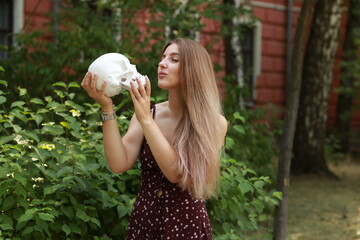 Young woman with a skull in her hands in the park