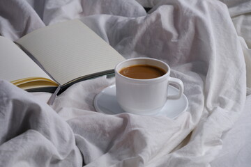 Coffee with milk and a notebook in bed. Breakfast in bed. Interior. Cosiness.