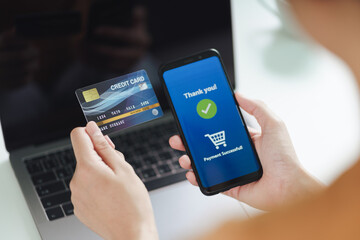 Young woman holding credit card and using smart phone for online shopping, internet banking, e-commerce, spending money, working from home concept