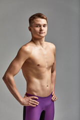 Fototapeta premium Young swimmer in excellent physical shape, on a gray background with copy space, call for sports, advertising banner