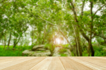 Empty top wooden table on soft blurred green tree in nature