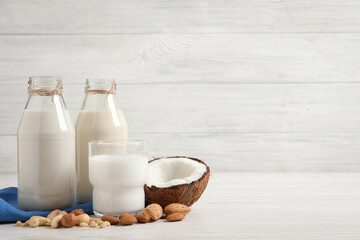 Different nut milks on white wooden table. Space for text