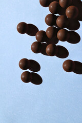 Dark chocolate bonbons with strong pastel blue background shadows