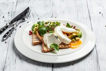 Breakfast. Poached eggs on toasted bread with avocado in plate on wooden background. banner, menu, recipe place for text, top view