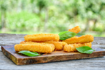 Vegetarian cheese breaded  oven baked  mozzarella sticks with  fresh basil on wooden background 