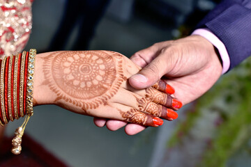 Closup of Indian Young adult male groom and female bride holding hands