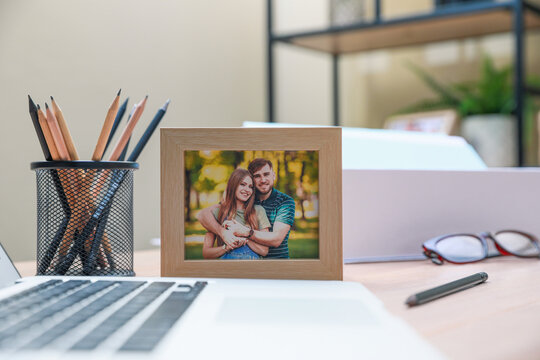 Framed photo of happy couple near laptop on wooden table in office