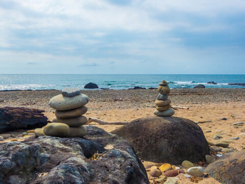 Two stone stack cairn on the sea rock at beach with driftwood. From Tamsui, New Taipei.