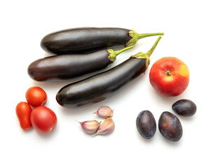 Eggplants, tomatoes, garlic, plums and apple on a white table background. Set cooking a delicious vegetable spicy dish. Fresh harvest.