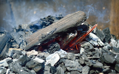 close-up - a flaming fire in an iron barbecue, charcoal, smoke and fire