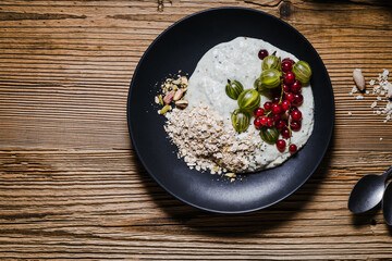 Breakfast smoothie bowl with gooseberries, red currants, rolled oats, pistachios