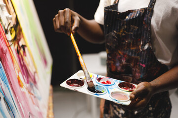 Fototapeta premium African american male painter at work painting on canvas in art studio