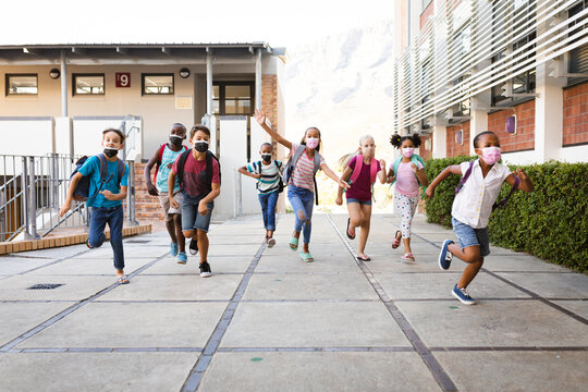 Group Of Diverse Students Wearing Face Masks Running At Elementary School