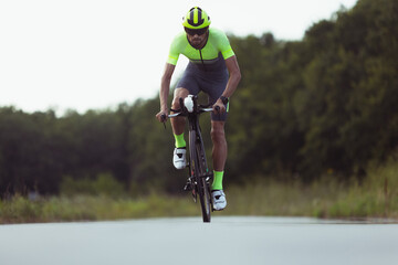 Young male triathlete riding a bicycle on the open road. Professional sportsman is engaged in...