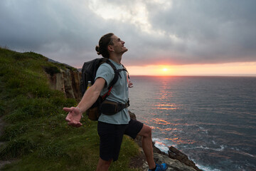 Traveling man enjoying freedom with outstretched arms on rock