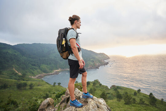 Male hiker standing on rock above sea