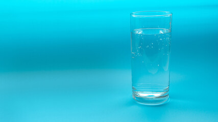 Glass with water isolated on a blue background. Copyspace.