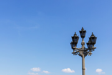 Street lamp against blue bright sky at summer